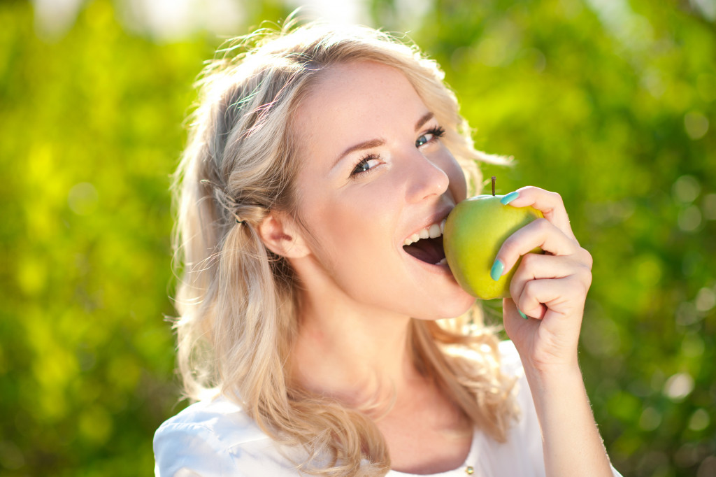 woman eating green apple