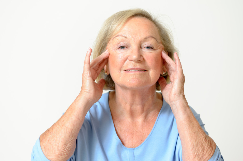 An elderly woman holding her face