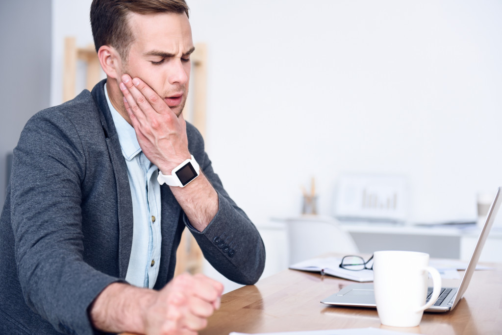 A man working on an office, experiencing jaw pain